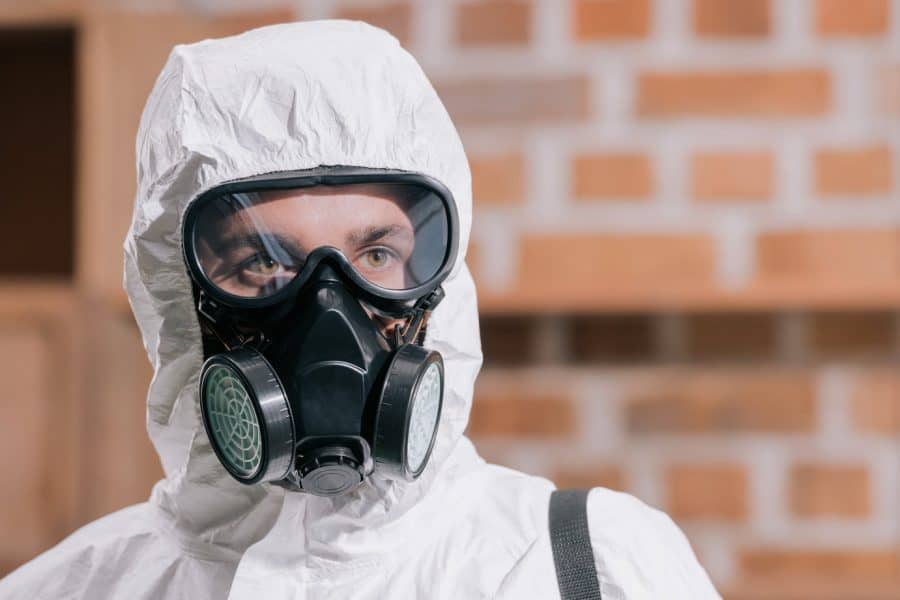 Asbestos, Lead & Mold Services - Worker in a hazmat suit and gas mask getting ready for work