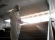 Occupational Exposure Limits (OELs) man inside a hazmat suite spraying, disinfectant